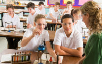 Schoolchildren and teacher in science class performing experiment